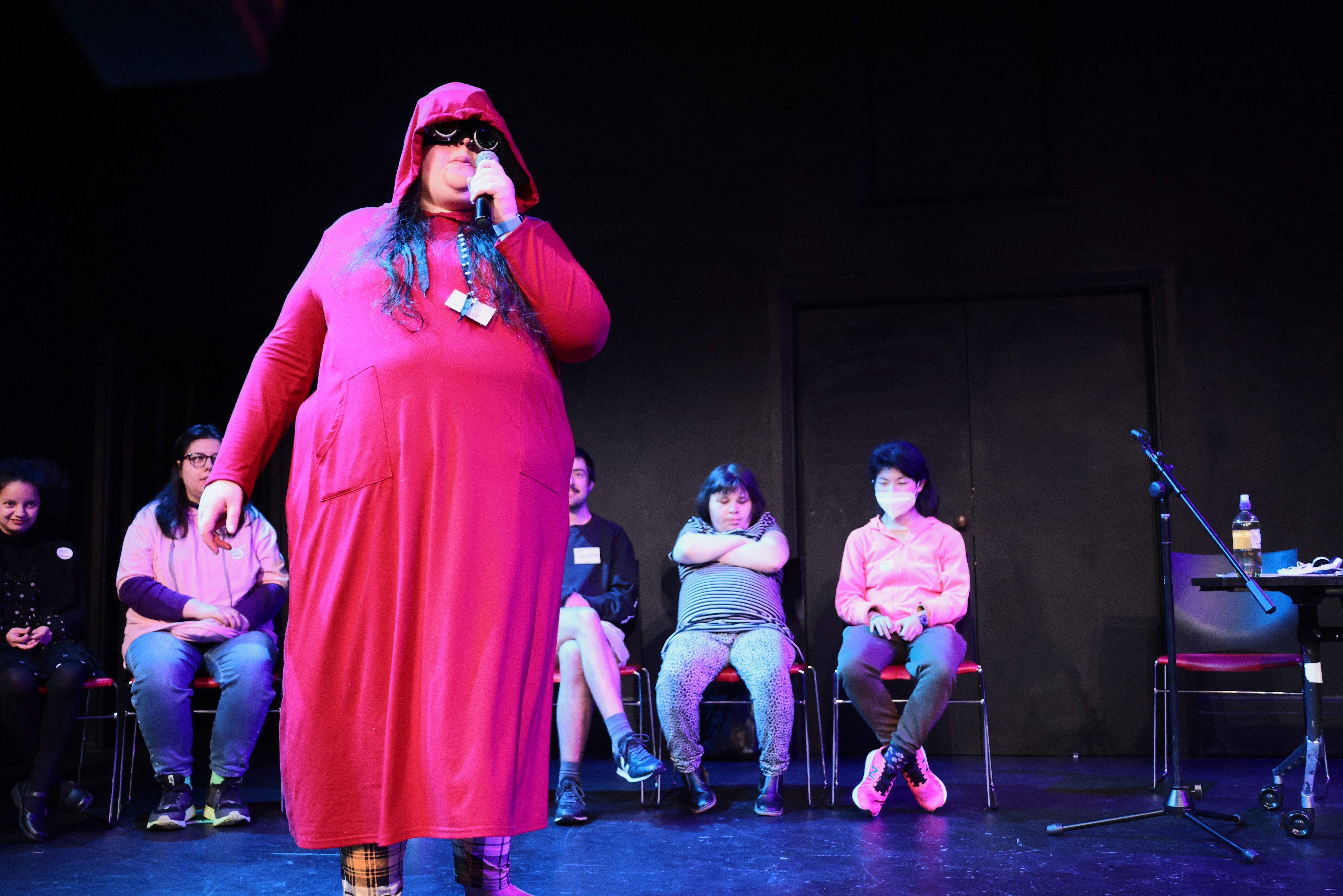 Susan Williams stands on-stage holding a microphone at DAT Fest 2024
