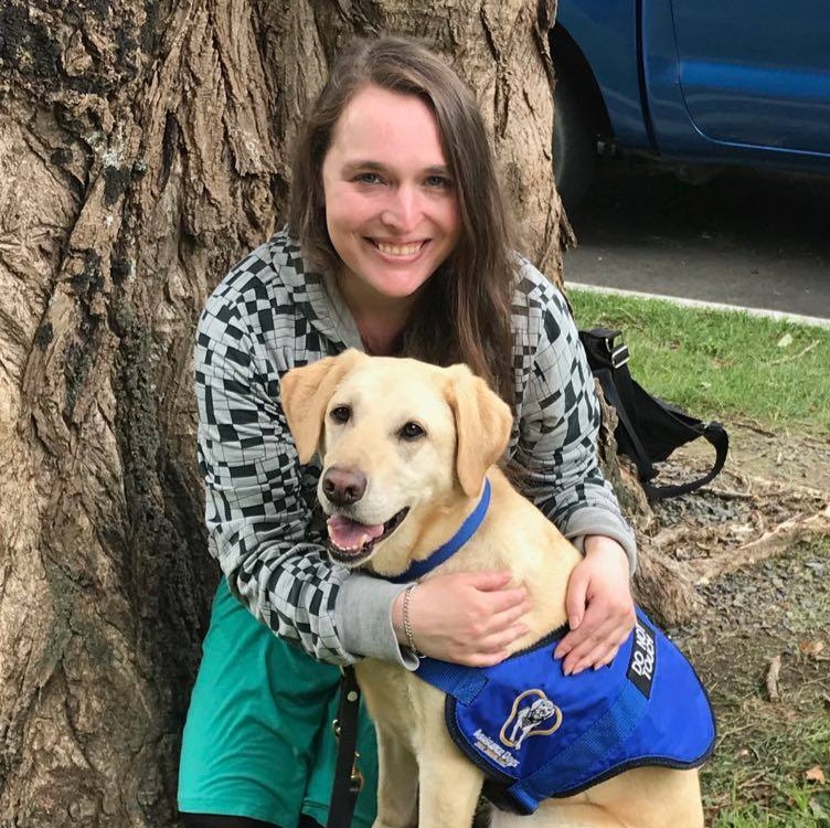 Artist bio photo: Helen Vivienne Fletcher Helen crouches beside a tree to hug her assistance dog, Bindi.