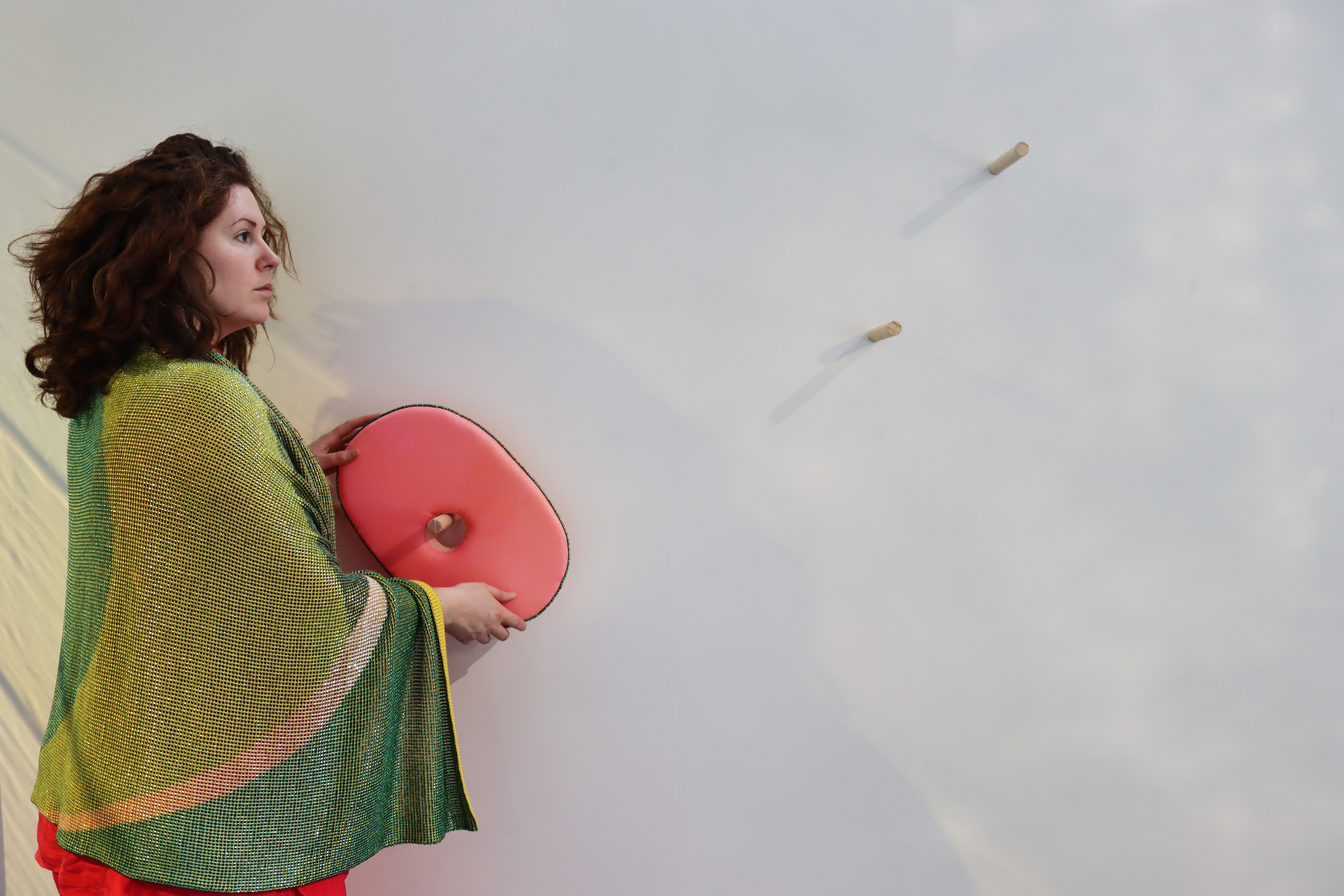 Opportunity Image Bailee Lobb stands holding one of her artworks - a red, oval shaped object with a hole in the middle.